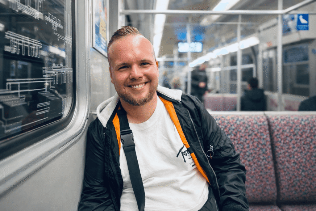 Authentisches Über-mich-Porträt eines lächelnden Mannes im Alltag, aufgenommen in einer U-Bahn